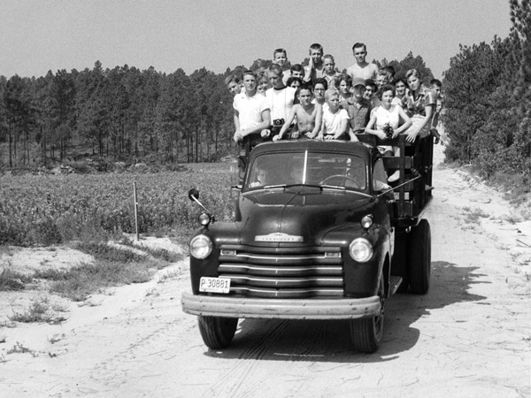 about us - campers piled into back of truck, photo from 1950's.