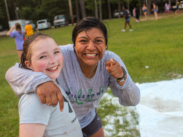 camper and counselor hug and smile after going down water slide