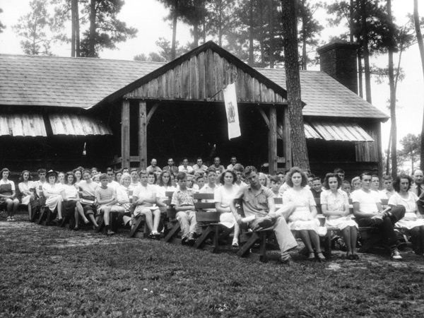 group of campers sitting in chairs outside of the dining hall from 1940's or 50's